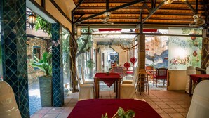 A room with a red table, white chairs, and a potted plant. There is a window with a view of the outside. - Vien Ngoc Xanh 1 Hotel (Ho Chi Minh City)