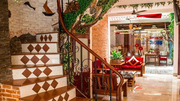 A staircase with a brick base and patterned steps, leading to a room with a red sofa and a table. - Vien Ngoc Xanh 1 Hotel (Ho Chi Minh City)