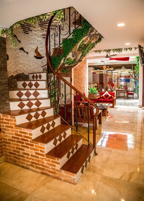 A staircase with a brick base and patterned steps, leading to a room with a red sofa and a table. - Vien Ngoc Xanh 1 Hotel (Ho Chi Minh City)