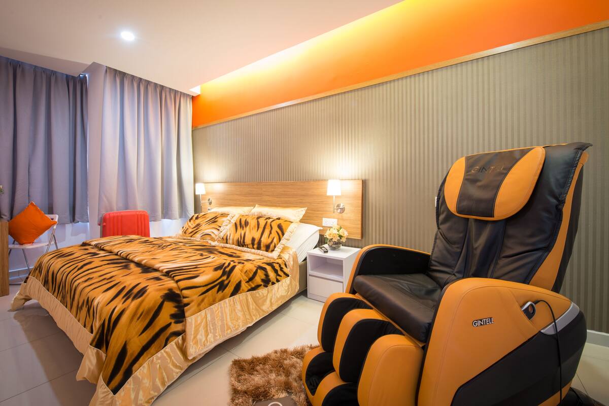 Ein Hotelzimmer mit einem Bett, einem Massagesessel, einem Nachttisch und einem roten Sessel.