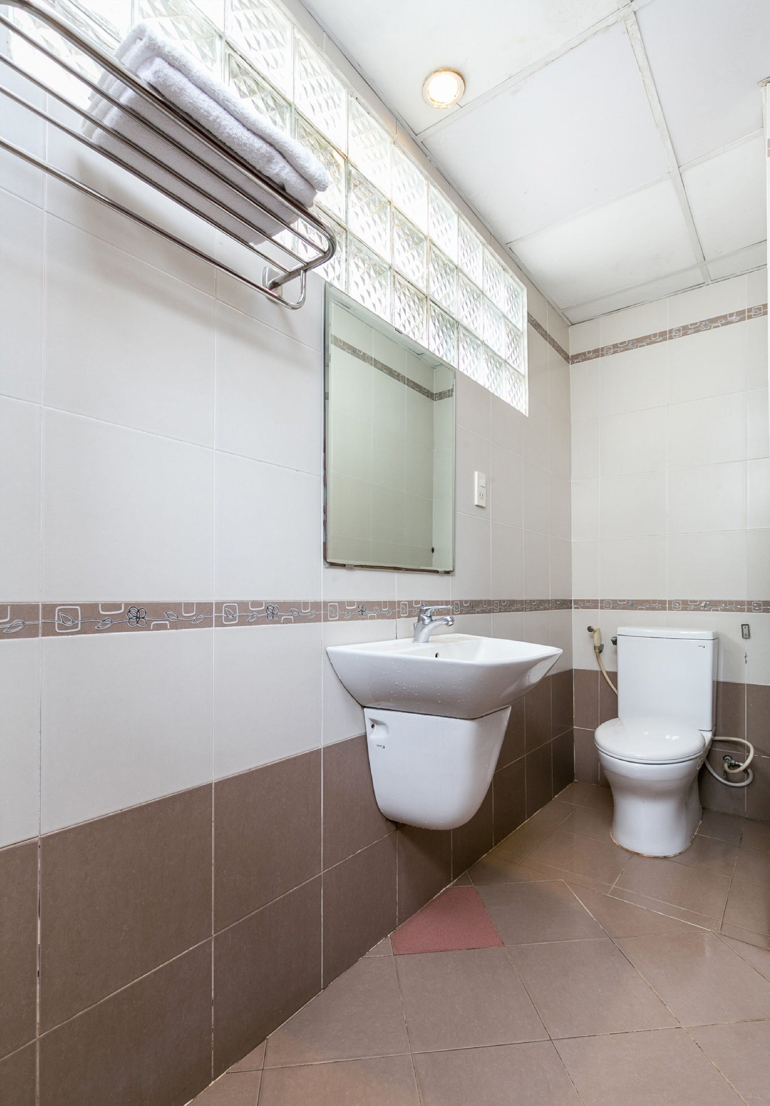 Un baño con lavamanos, inodoro y perchero para toallas.