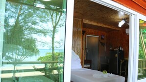 A room with a bed, a desk, and a view of the ocean.