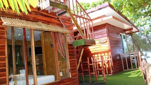 A wooden cabin with a spiral staircase, large windows, and a small deck area.