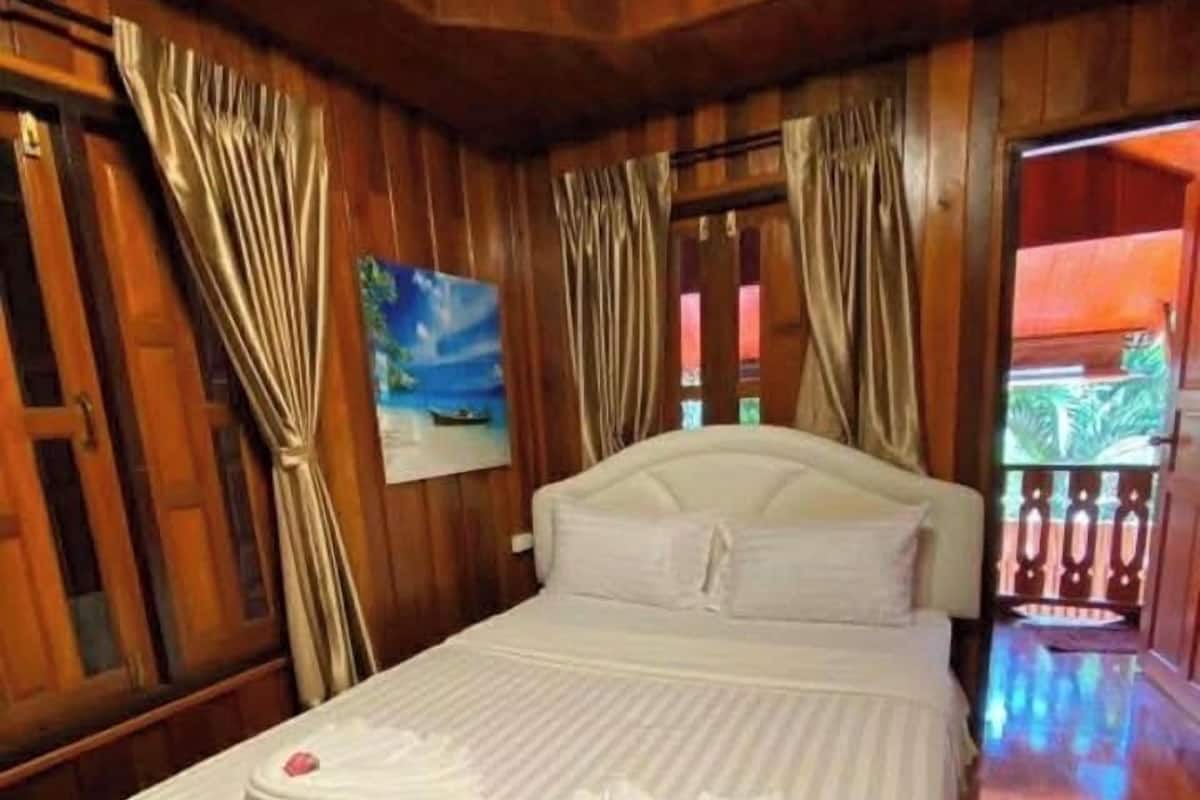 A wooden room with a bed, curtains, and a painting.