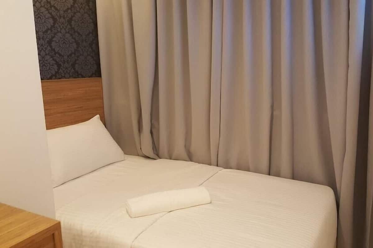 Ein Hotelzimmer mit Bett, Vorhängen, einem Holz-Kopfteil, einem Flachbildfernseher und einer Wand mit Muster.