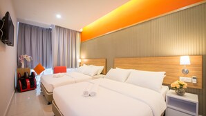 A hotel room with two beds, a massage chair, a TV, and a nightstand with a lamp and flowers.