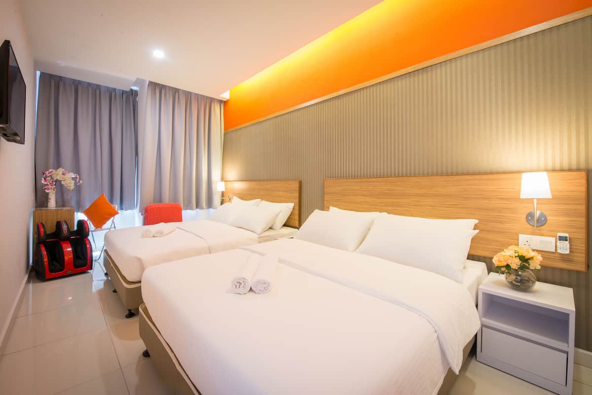 Ein Hotelzimmer mit zwei Betten, einem Massagesessel, einem Fernseher und einem Nachttisch mit Lampe und Blumen.