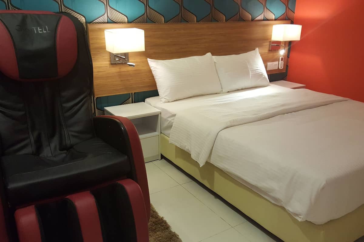 Ein Hotelzimmer mit einem Bett, einem Sessel, zwei Nachttischlampen und einem Nachttisch.
