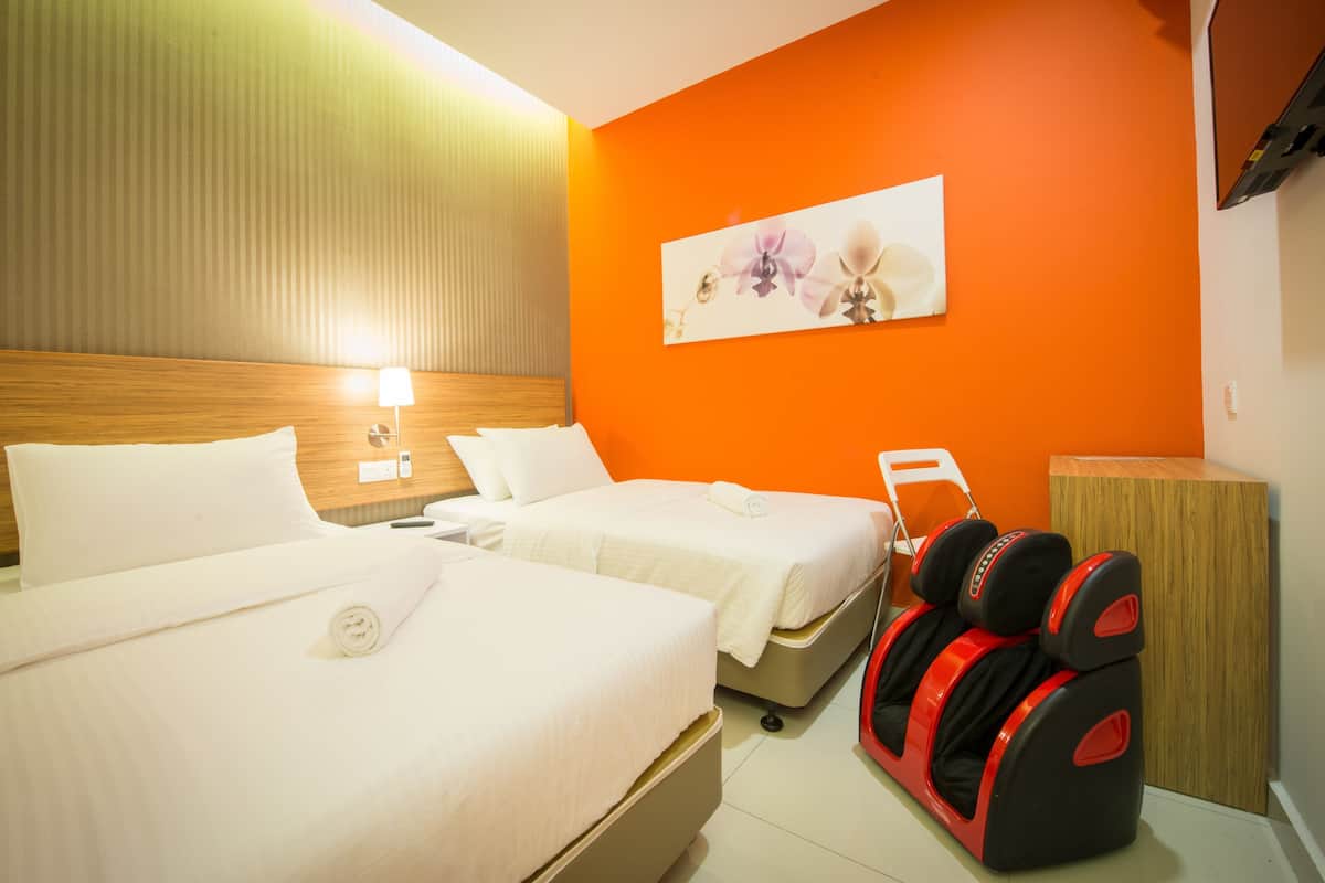 Ein Hotelzimmer mit zwei Betten, einem Massagesessel und einem hölzernen Kopfteil.