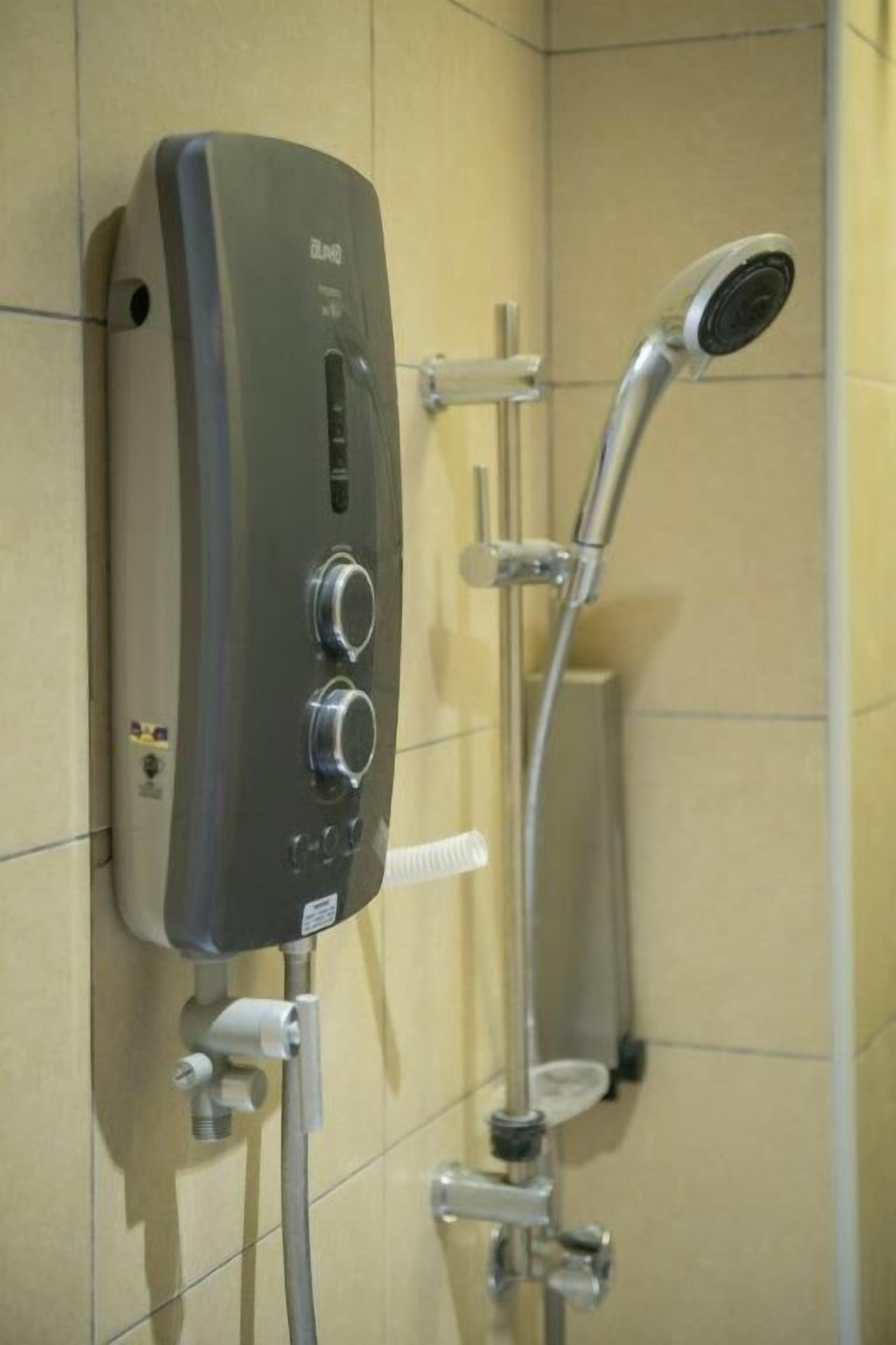 A wall-mounted shower unit with control knobs and a handheld showerhead.