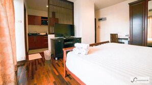 Habitació d'hotel amb llit, escriptori, televisió i petita cuina.