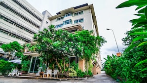 Un edifici modern amb diverses plantes, envoltat de vegetació exuberanta i un passeig pavimentat.