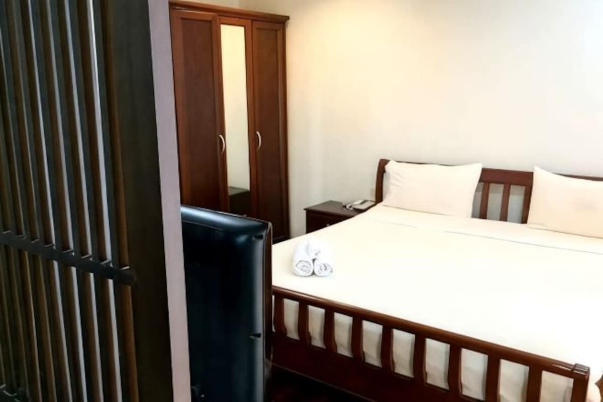 A bedroom with a bed, a nightstand, a wardrobe, and a mirror.