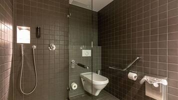 Une salle de bain moderne dotée d’une douche à parois de verre, de toilettes et d’un sèche-mains.