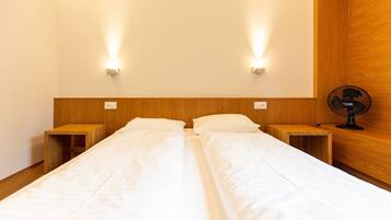 A double bed with two wooden nightstands, each with a small shelf and a wall-mounted light.