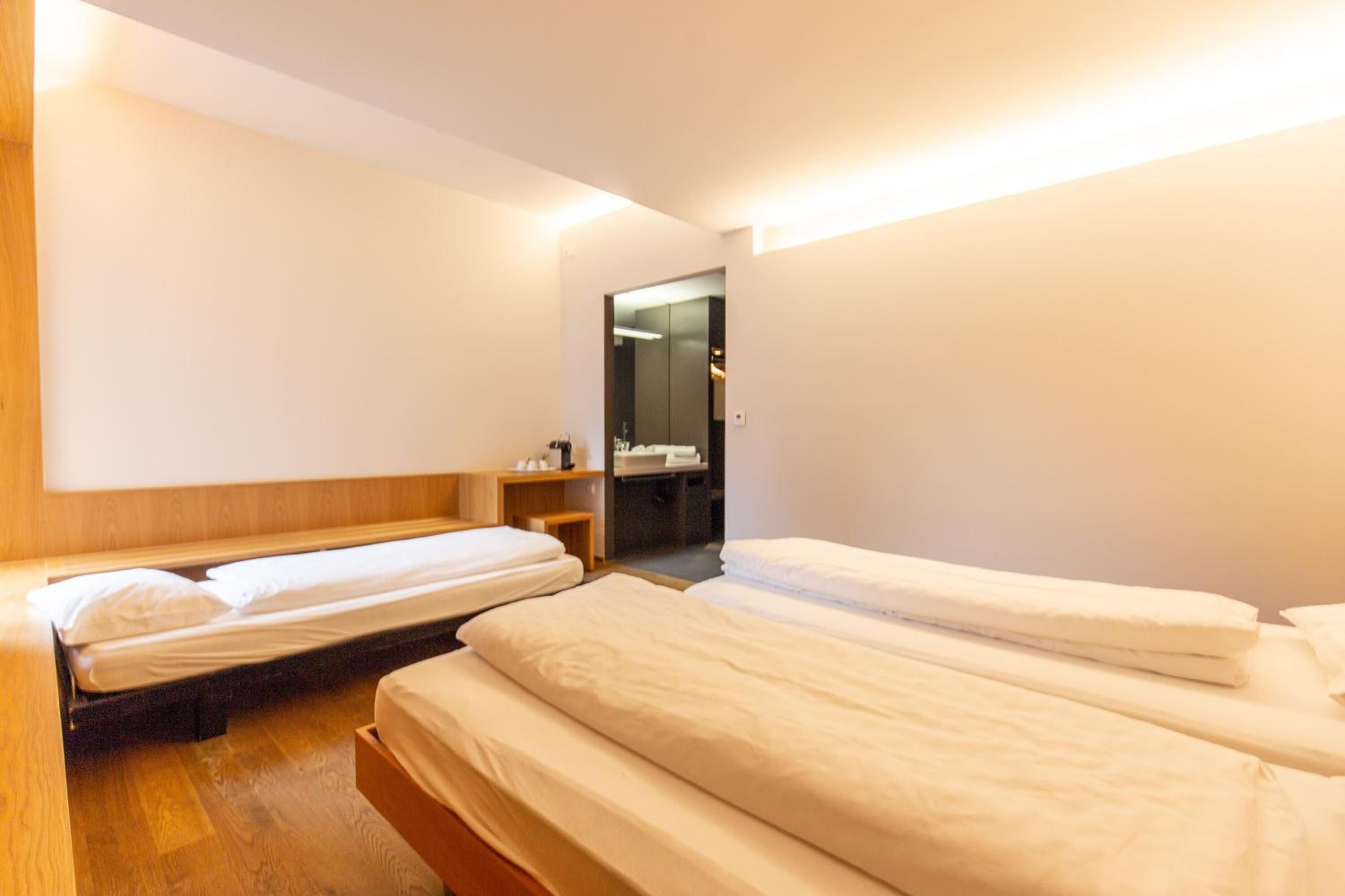 Una habitación de hotel con dos camas individuales, cabeceros de madera, una mesita de noche pequeña y un espejo.