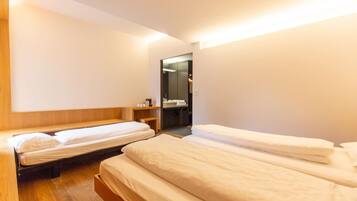Una habitación de hotel con dos camas individuales, cabeceros de madera, una mesita de noche pequeña y un espejo.