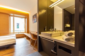 A modern hotel room with a bed, desk, and a large mirror. - Hyve Hotel Basel - Hostel (Basel)