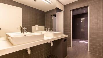 A modern bathroom with two sinks, a large mirror, and a dark tiled floor.