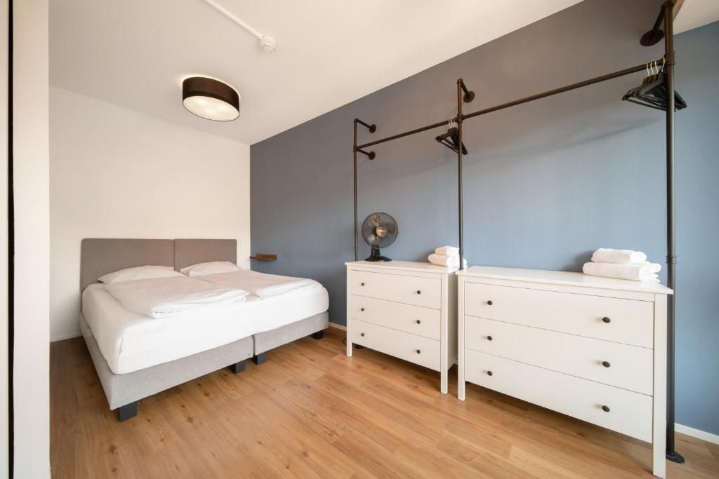 Ein Schlafzimmer mit Bett, Kommode, Spiegel und Deckenventilator.