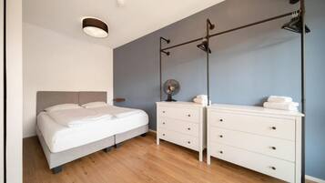 Ein Schlafzimmer mit Bett, Kommode, Spiegel und Deckenventilator.