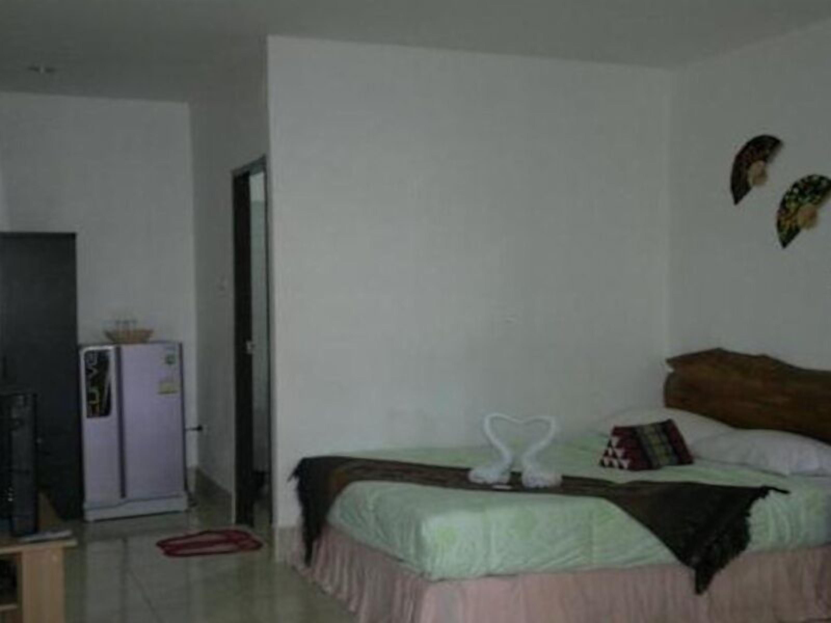 Un dormitorio con cama, televisión y refrigerador.