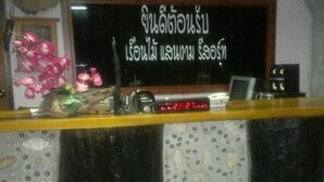 A reception desk with a clock displaying 22:27, a small potted plant, and a framed picture. - Ruan Mai Sang Ngam Resort (Sa Khu)