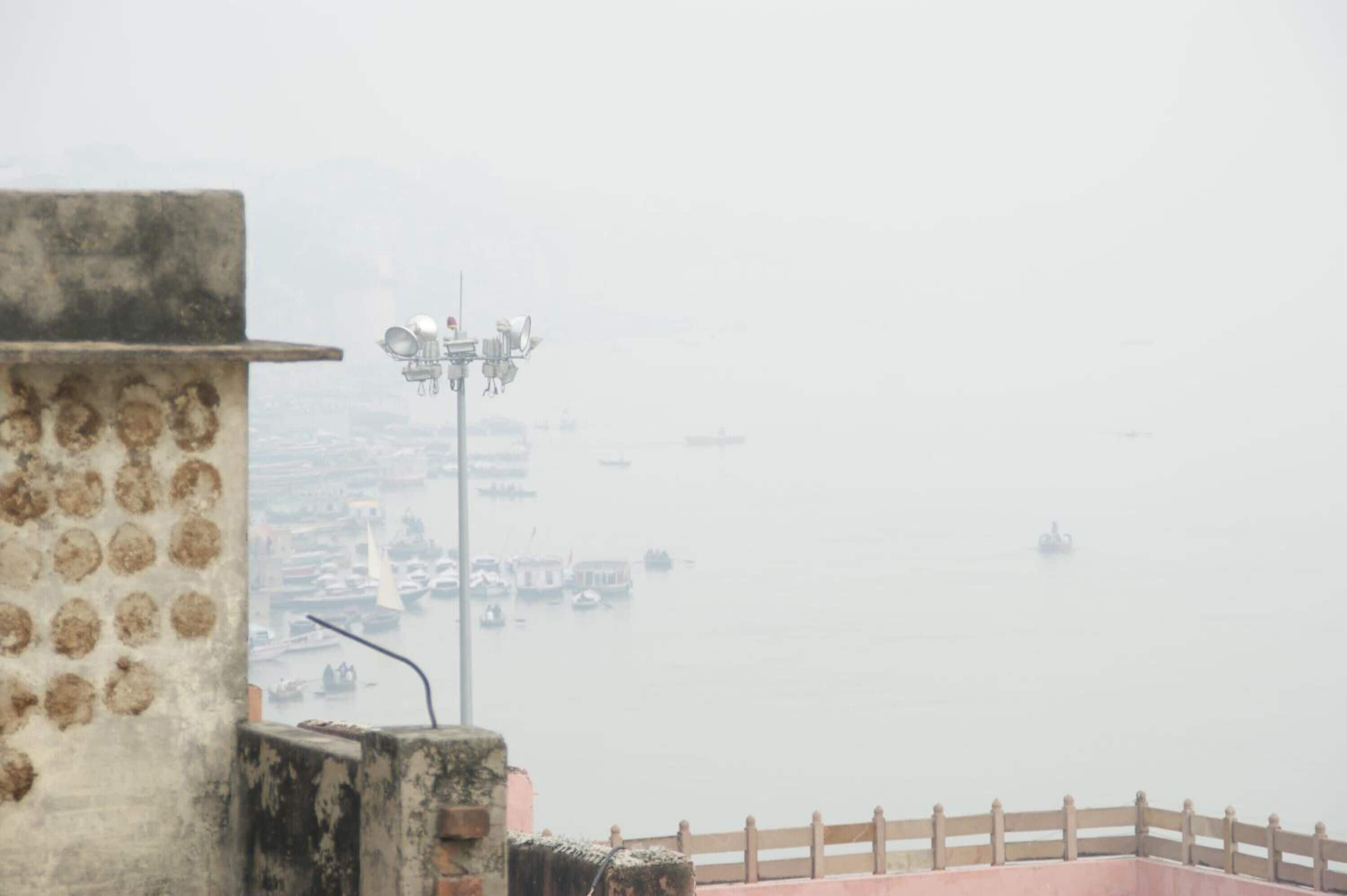 A foggy waterfront view with a building and a street lamp.