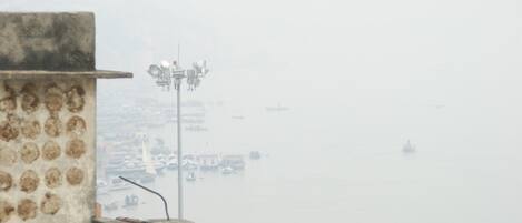 A foggy waterfront view with a building and a street lamp.