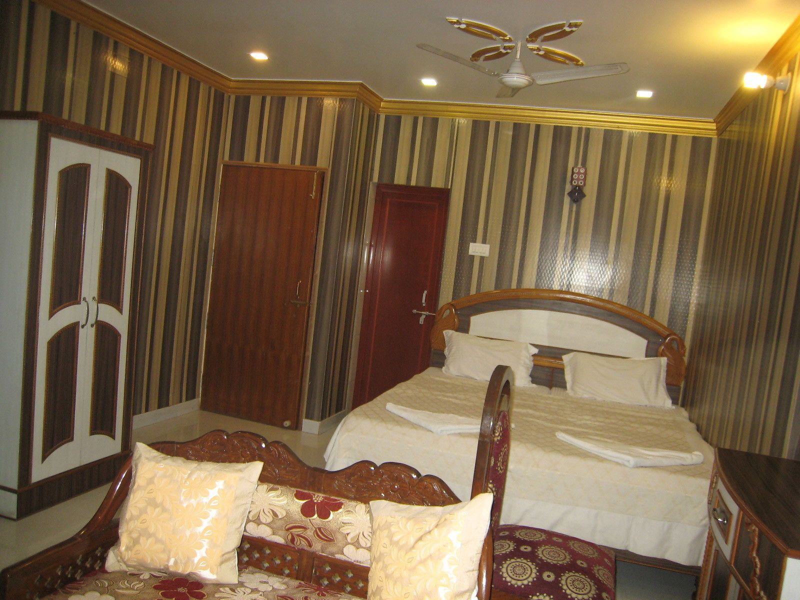 A bedroom with a bed, a wardrobe, and a ceiling fan.