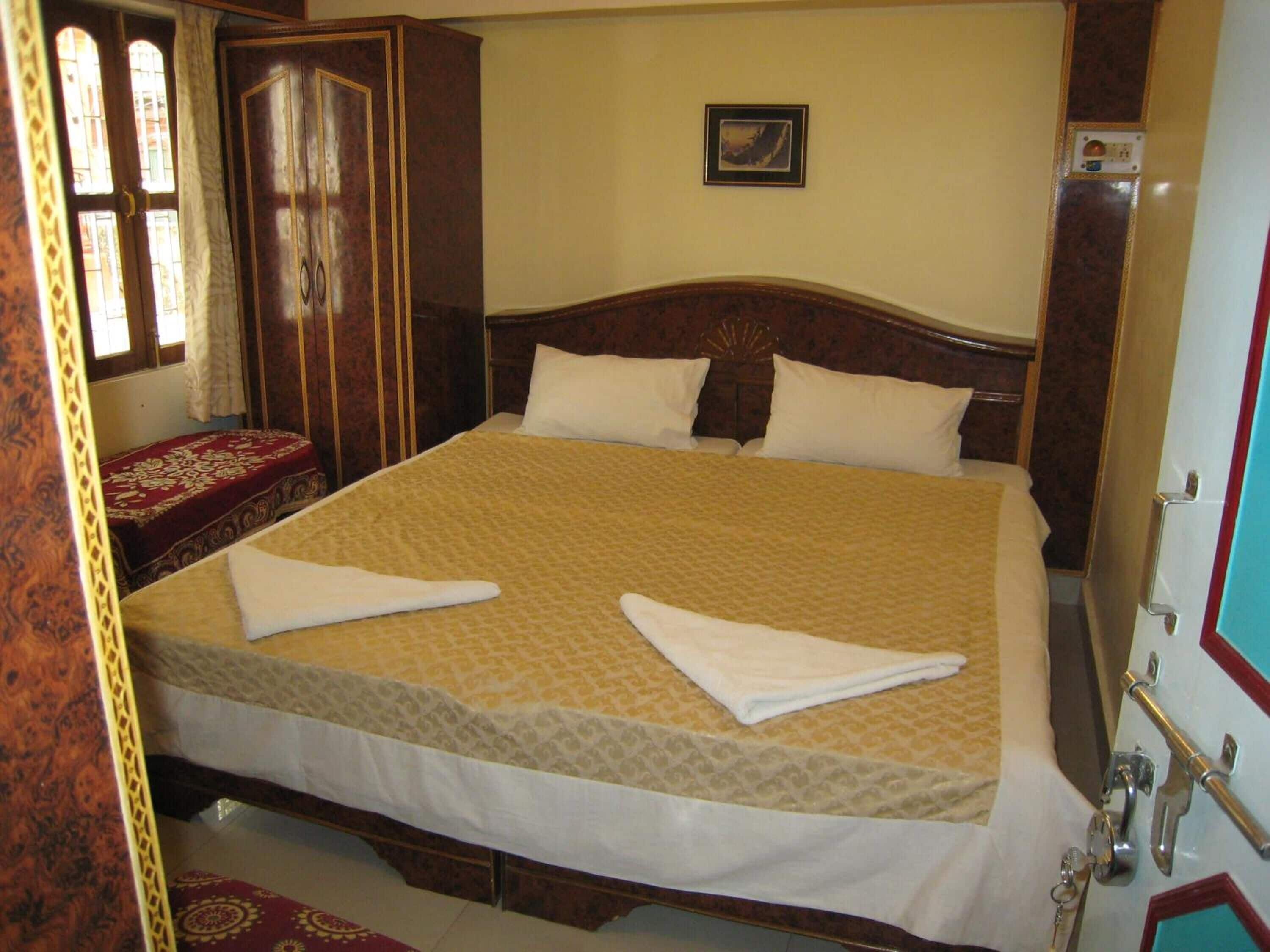 A large bed with a patterned bedspread, two pillows, and a wooden headboard.