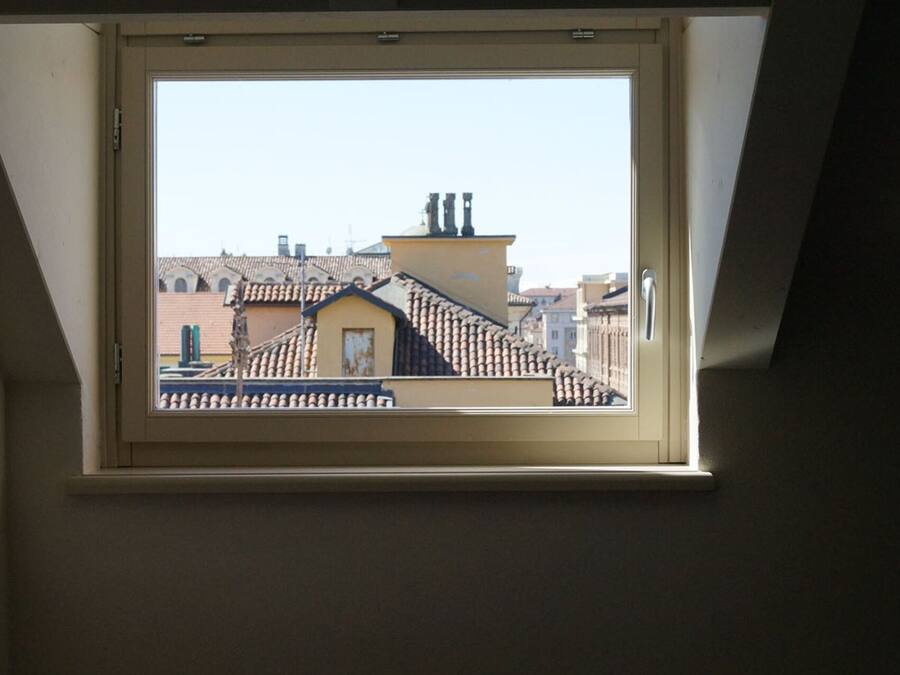 A skylight window with a view of a building's roof and chimney.