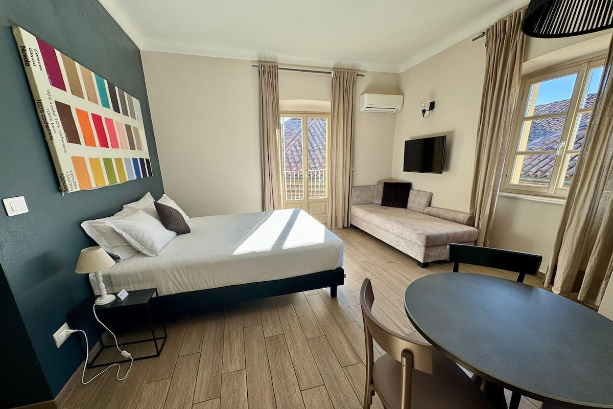 Una habitación de hotel con cama, sofá, mesa y televisión.