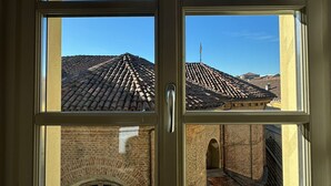 A window with a view of a building with a tiled roof and brick walls. - Residenza dell'Opera (Turin)