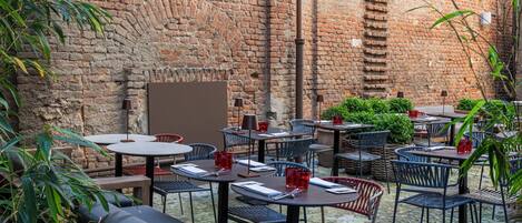 A courtyard with outdoor seating, brick walls, and potted plants.