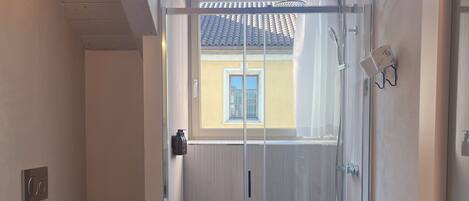 A modern bathroom with a glass shower enclosure, a toilet, and a sink.