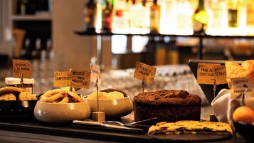 Variedad de productos horneados expuestos en un mostrador, con etiquetas que indican diferentes tipos de pasteles y galletas.
