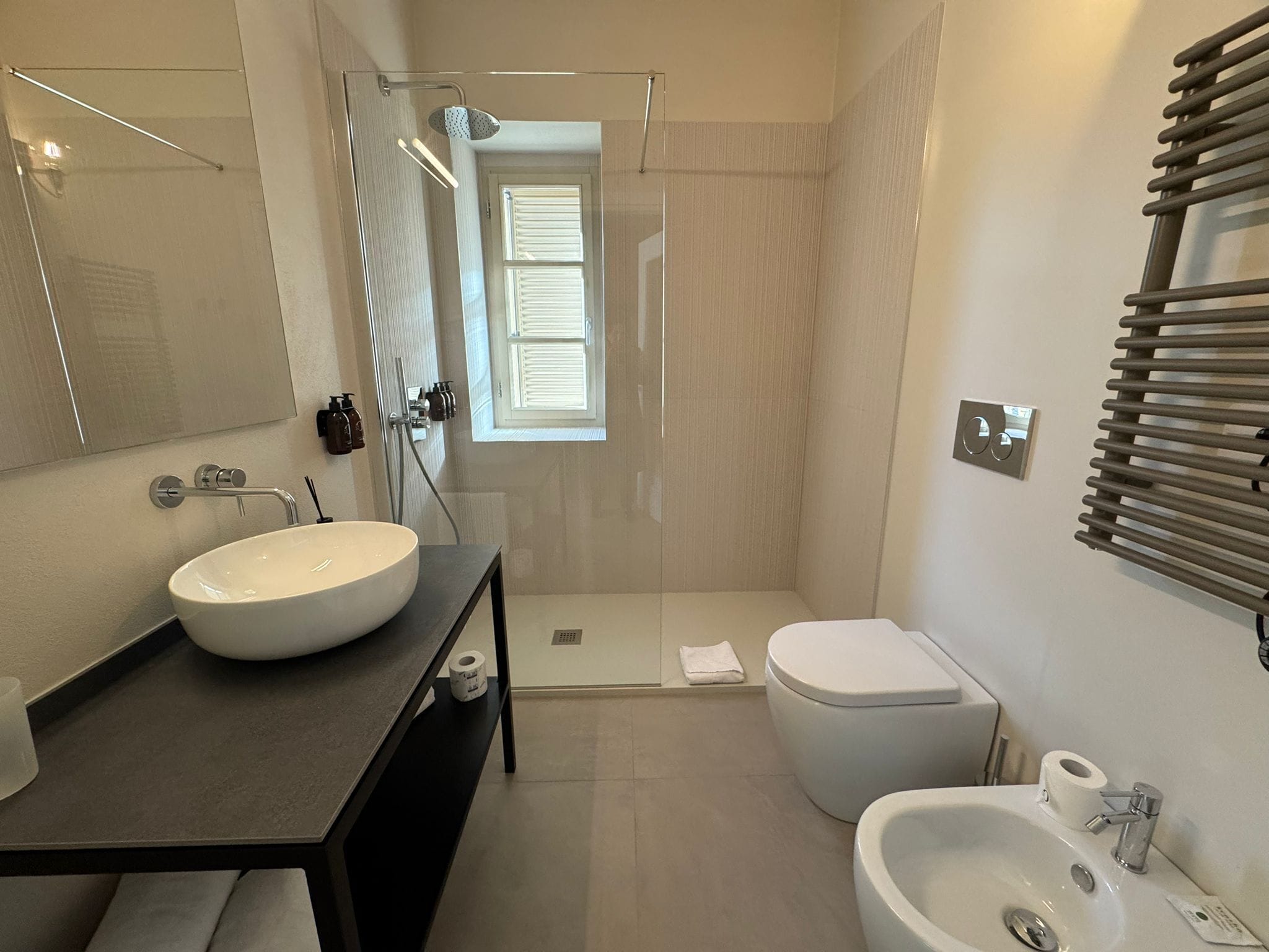 A modern bathroom with a large sink, a toilet, and a shower area.