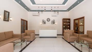 A reception area with a reception desk, two sofas, and a glass coffee table.