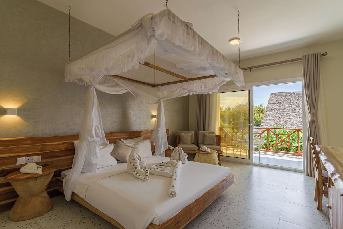 Un dormitorio amplio con una cama de madera, dosel y un balcón con vistas.
