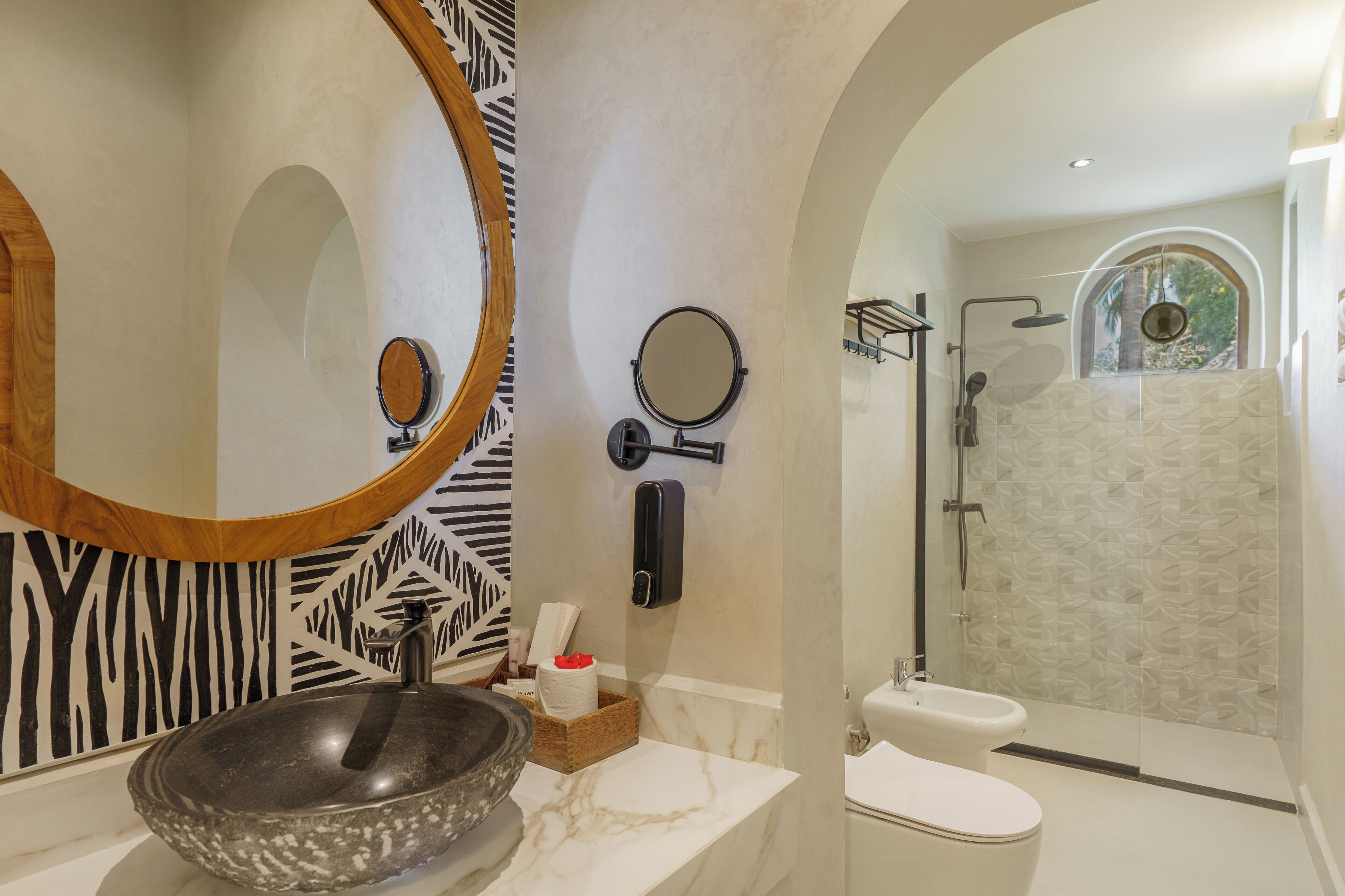 Een badkamer met een groot ovaal wastafel, twee spiegels, toilet en een douche.