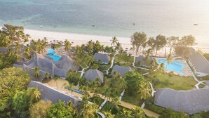 Un resort con varias cabañas, un área de piscina central y vistas a la playa.
