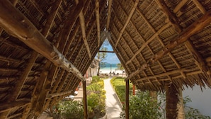 Una edificación con techo de paja y un sendero que conduce a la playa.