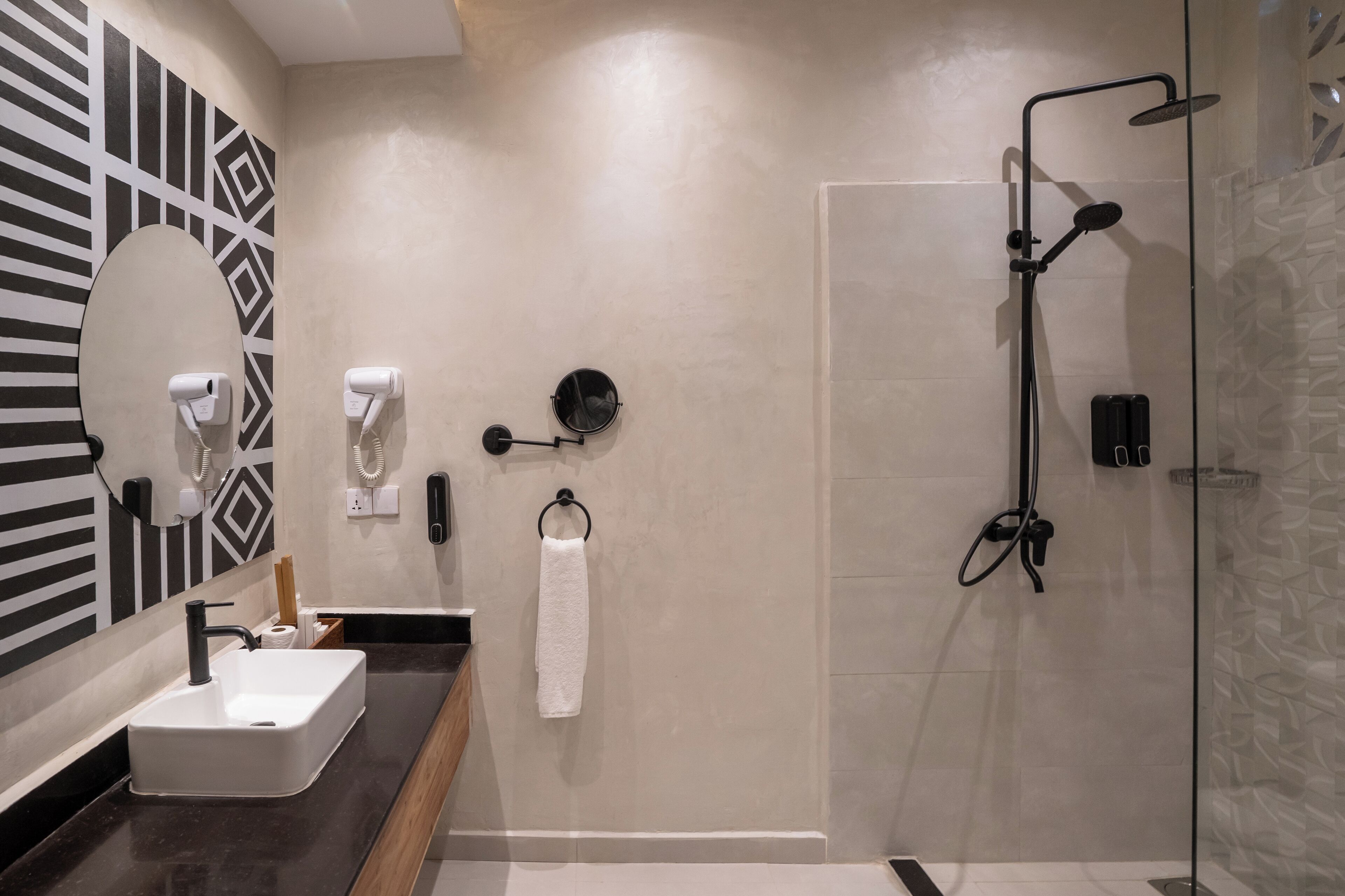Une salle de bain moderne avec un grand miroir, un lavabo, un porte-serviettes et une douche à l’italienne.