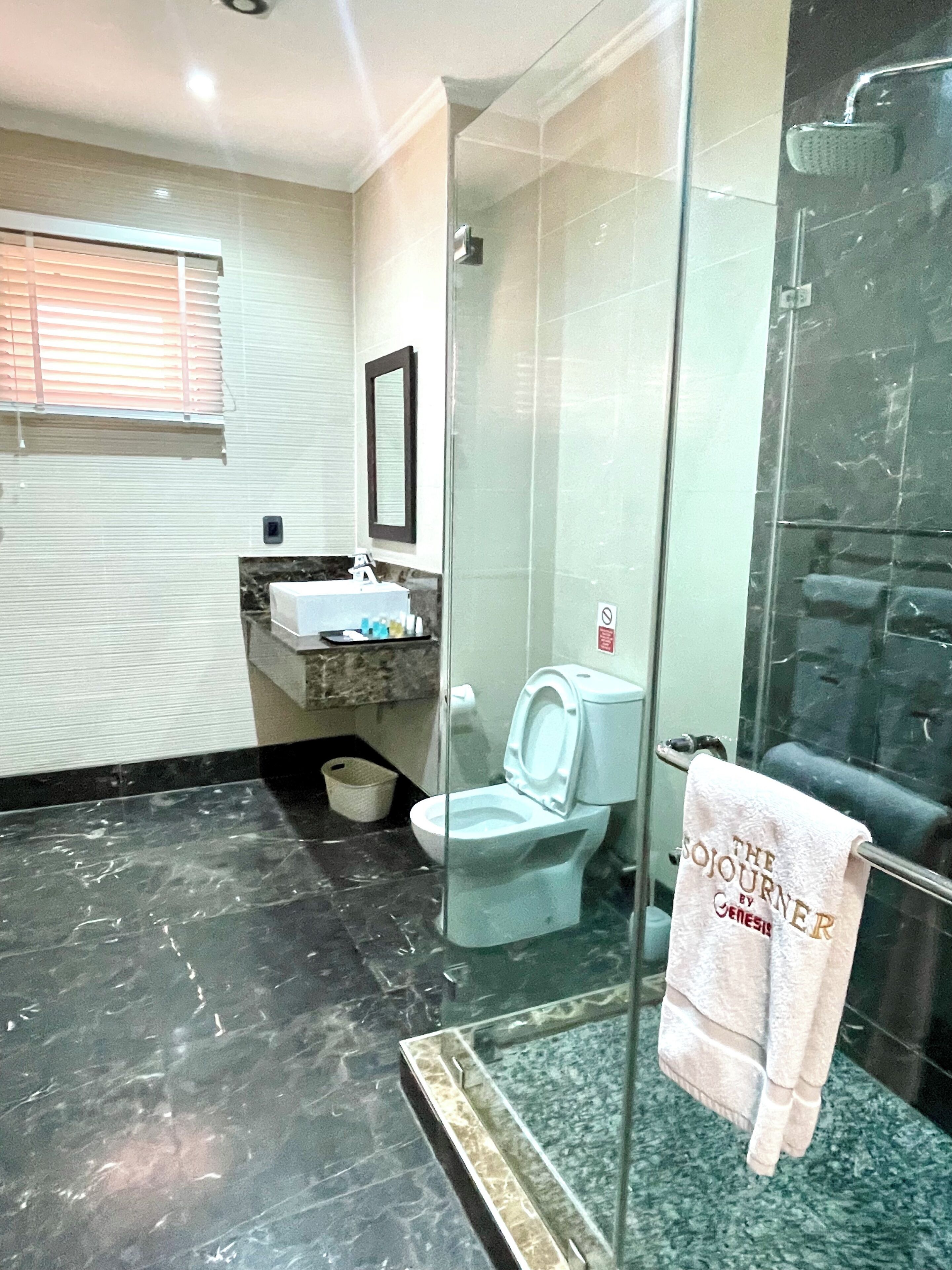 A bathroom with a glass-enclosed shower, a toilet, a sink, and a towel rack with a towel hanging on it.