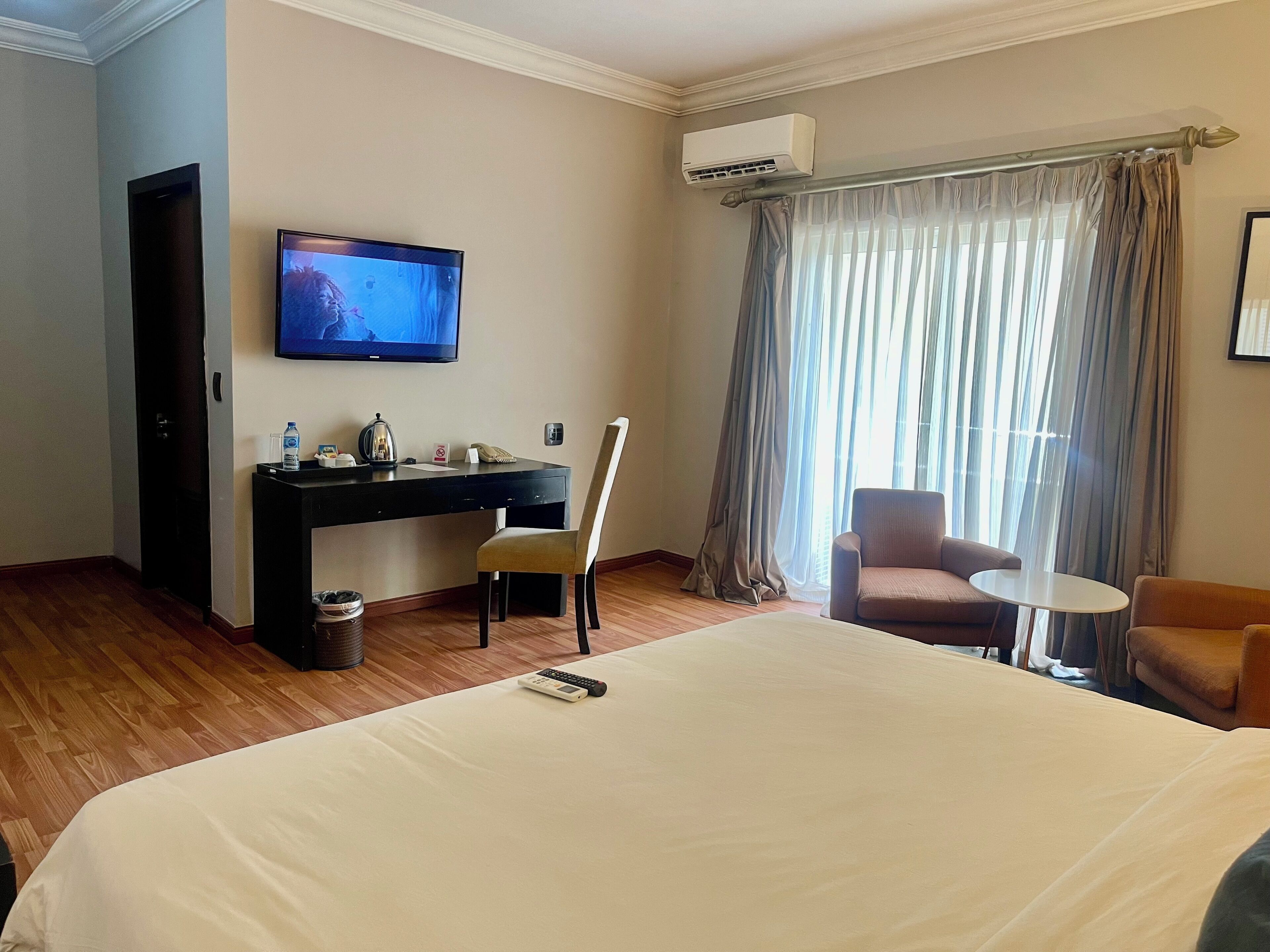 Een hotelkamer met een bed, een bureau met stoel, een televisietoestel en een raam met gordijnen.