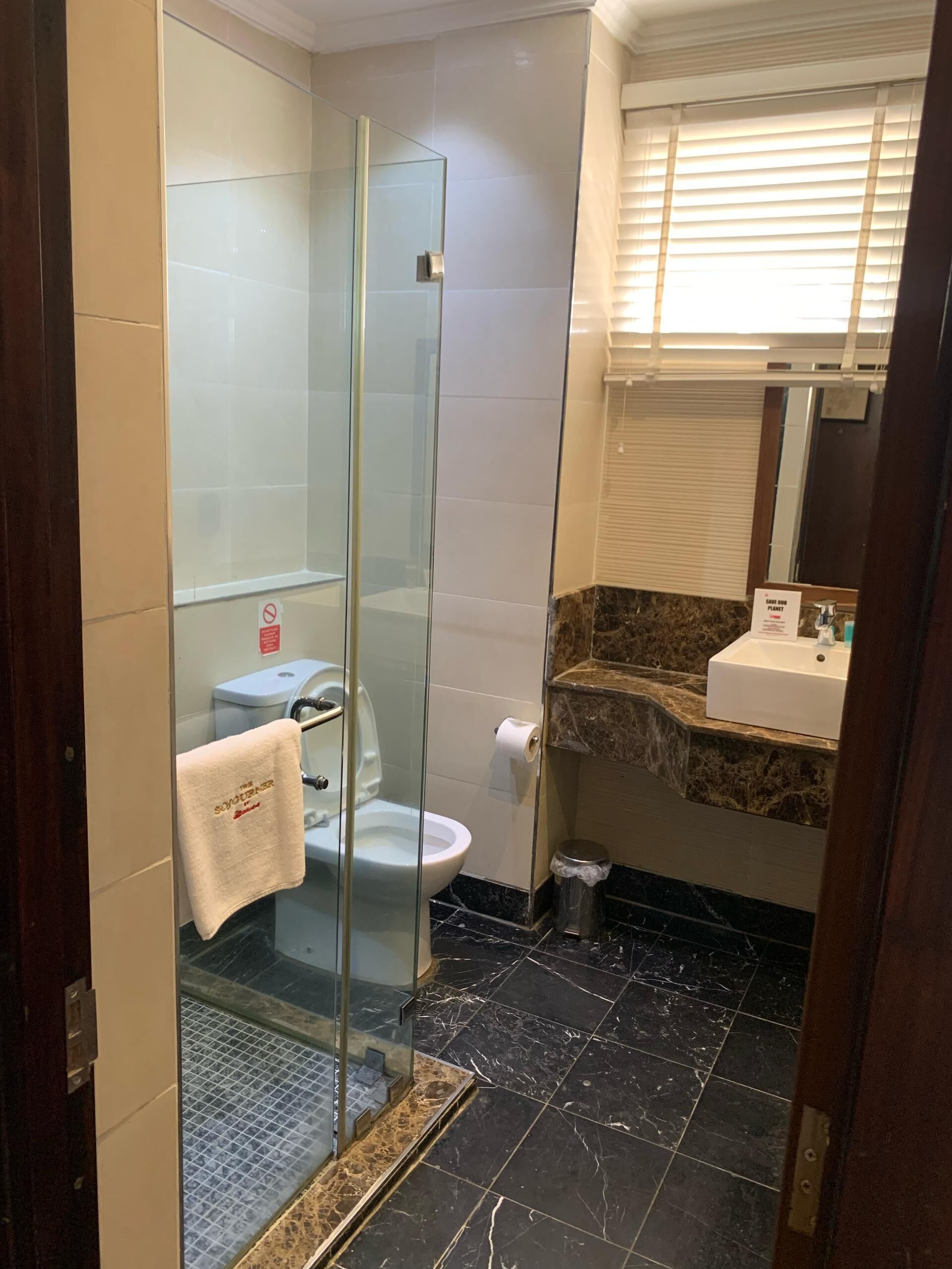 Une salle de bain dotée d’une douche à parois de verre, de toilettes et d’un lavabo avec un plan de travail en marbre.