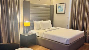 Una habitación de hotel con cama, mesitas de noche, un escritorio, una silla y una mesa redonda.