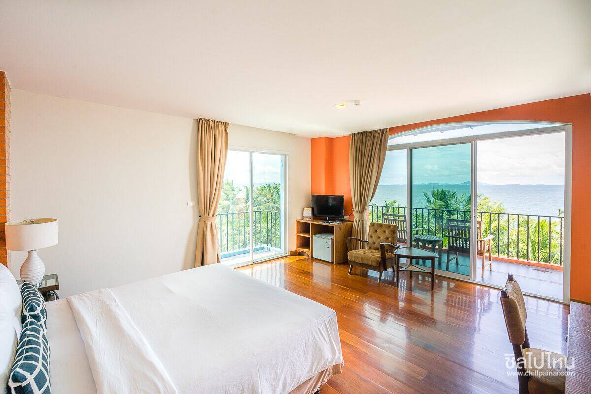 Una habitación de hotel con cama, televisión, escritorio y balcón con vista al mar.