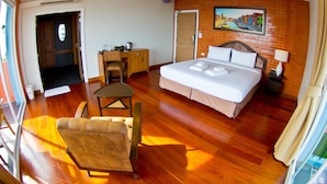 A hotel room with a bed, a desk, a chair, and a painting on the wall. - Coasta Bangsaen (Chonburi)